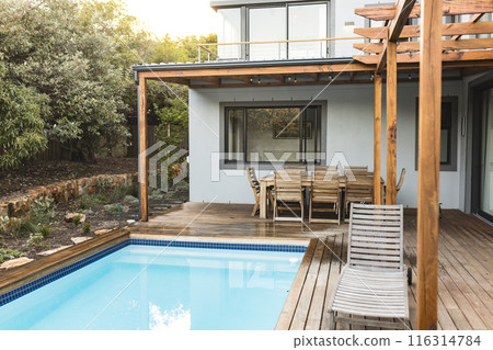Outdoor patio with wooden furniture and swimming pool, modern home setting, copy space Outdoor patio with wooden furniture and swimming pool, modern home setting, copy space 116314784