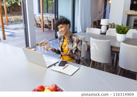 Video calling on laptop, teenage boy gesturing and smiling in modern kitchen, copy space Video calling on laptop, teenage boy gesturing and smiling in modern kitchen, copy space 116314909