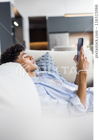 Relaxing on couch, teenage boy using smartphone and browsing at home 116315066