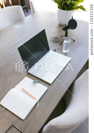 Laptop, notebook, and microphone on wooden table for home office setup 116315168