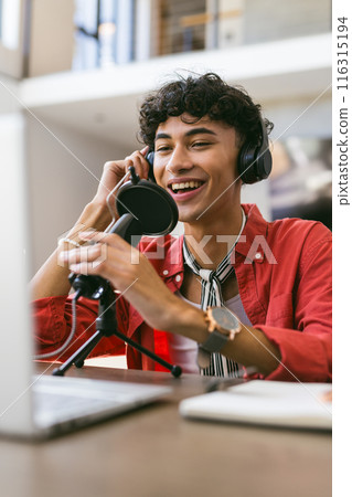 Recording podcast, smiling young man using microphone and laptop at home studio Recording podcast, smiling young man using microphone and laptop at home studio 116315194