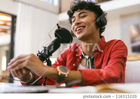 Recording podcast, teenage boy speaking into microphone wearing headphones Recording podcast, teenage boy speaking into microphone wearing headphones 116315220