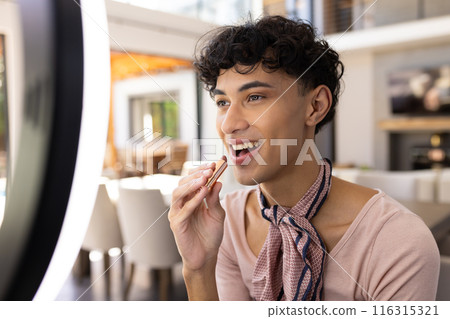 Applying lipstick, transgender transgender woman smiling in front of ring light at home Applying lipstick, transgender transgender woman smiling in front of ring light at home 116315321