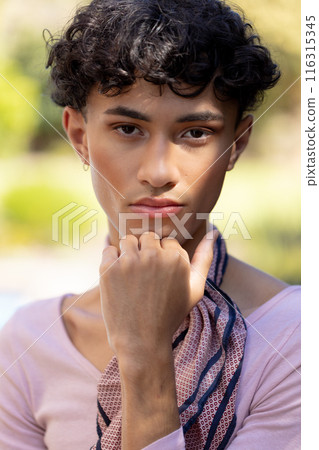 undefined posing confidently with hand on chin, wearing patterned scarf 116315345