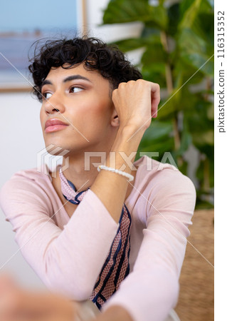 Contemplating, transgender transgender woman sitting at home with hand on chin Contemplating, transgender transgender woman sitting at home with hand on chin 116315352