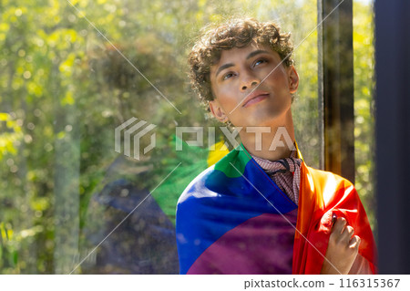 Reflecting by window, transgender woman wrapped in rainbow flag, embracing identity, copy space Reflecting by window, transgender woman wrapped in rainbow flag, embracing identity, copy space 116315367