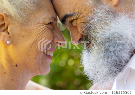 Senior bride and groom smiling and touching foreheads, at outdoor wedding 116315502