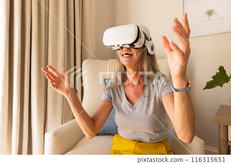 Using VR headset, mature woman enjoying virtual reality experience at home Using VR headset, mature woman enjoying virtual reality experience at home 116315651