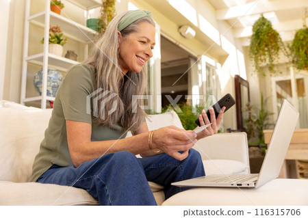 Shopping online, mature woman using smartphone and holding credit card with laptop 116315706