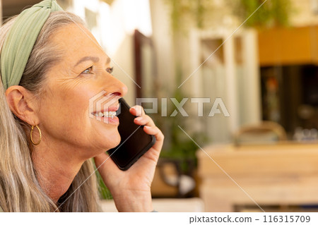 Smiling mature woman holding smartphone and talking, enjoying conversation at home, copy space Smiling mature woman holding smartphone and talking, enjoying conversation at home, copy space 116315709