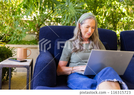 Using laptop, mature woman working from home on comfortable chair, copy space 116315723