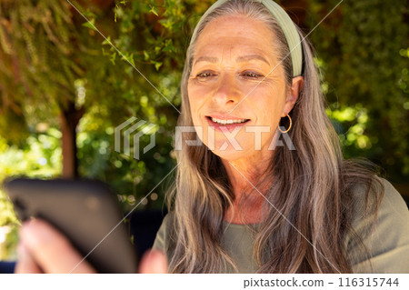 Using smartphone outdoors, mature woman smiling and enjoying leisure time Using smartphone outdoors, mature woman smiling and enjoying leisure time 116315744