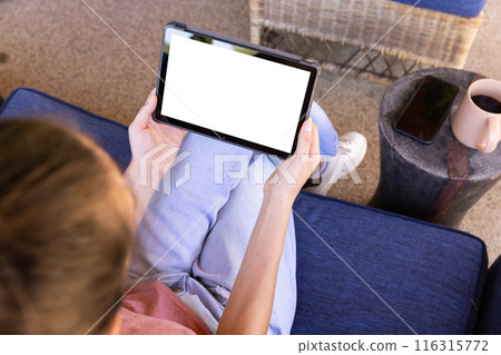 Using tablet while sitting on couch, young woman relaxing at home, copy space Using tablet while sitting on couch, young woman relaxing at home, copy space 116315772