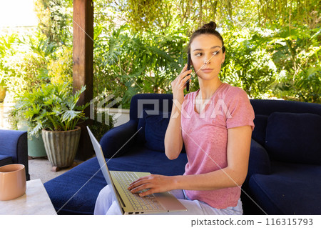Using laptop and talking on smartphone, woman working from home on patio 116315793