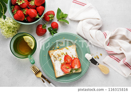 Toast with strawberrys, cottage cheese and pistachios and tea for breakfast. Sandwich, Bruschetta, snack, appetizers with strawberry. top view 116315816