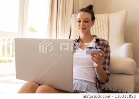 Shopping online, young woman holding credit card and using laptop at home, copy space 116315850