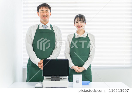 A male and female clerk who works at a cash register at a convenience store / supermarket / shop 116315907