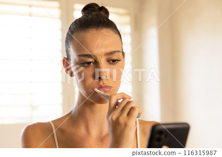Brushing teeth, woman using smartphone and focusing on screen at home Brushing teeth, woman using smartphone and focusing on screen at home 116315987