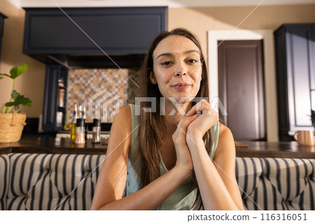Smiling woman sitting in kitchen, looking at camera, enjoying her home 116316051