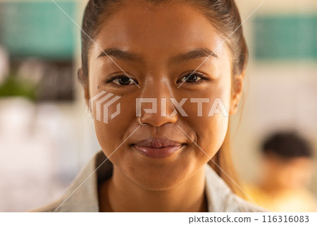 Smiling teenage girl in high school classroom, looking confidently at camera 116316083