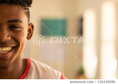 Smiling teenage boy enjoying moment in classroom at high school, copy space 116316096