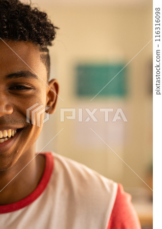 Smiling teenage boy in high school, wearing casual shirt, enjoying classroom environment, copy space 116316098
