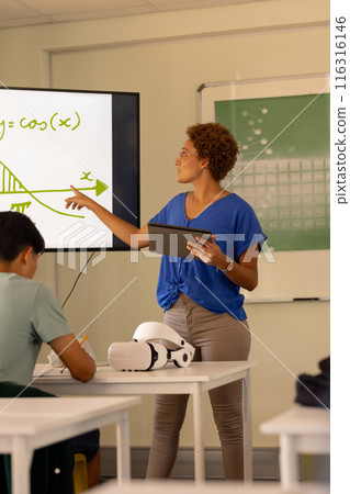 Teaching math, teacher using tablet and pointing at screen in high school classroom Teaching math, teacher using tablet and pointing at screen in high school classroom 116316146