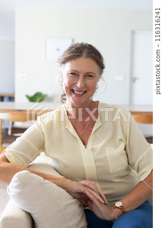 Smiling senior woman sitting on couch, enjoying relaxing vacation at home Smiling senior woman sitting on couch, enjoying relaxing vacation at home 116316241