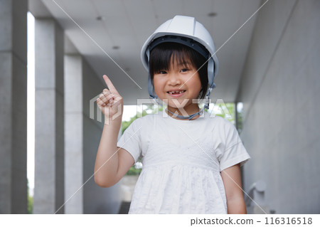 Smiling elementary school student wearing a helmet. Explanation image with pointing pose 116316518