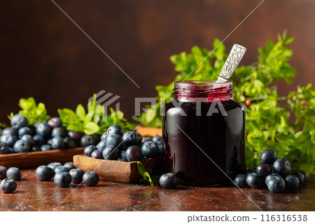 Blueberry jam and fresh berries on a brown background. 116316538