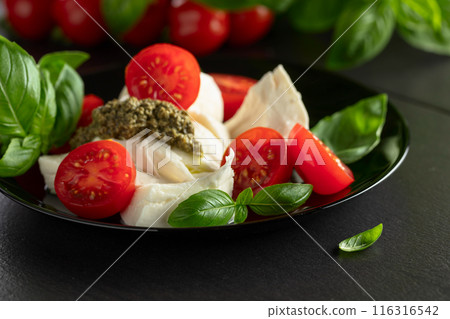 Mozzarella with basil, cherry tomatoes and pesto sauce. 116316542