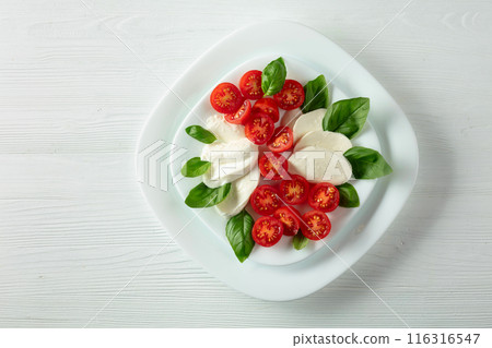 Mozzarella with basil and cherry tomatoes on a wooden table. 116316547