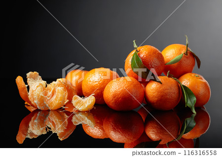 Tangerines or clementines with green leaves on a black background. 116316558