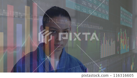 Image of graphs and number charts, serious biracial martial female artist standing against wall 116316605