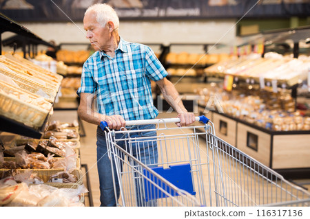 Mature senor choosing bread and baking in grocery section of supermarket Mature senor choosing bread and baking in grocery section of supermarket 116317136