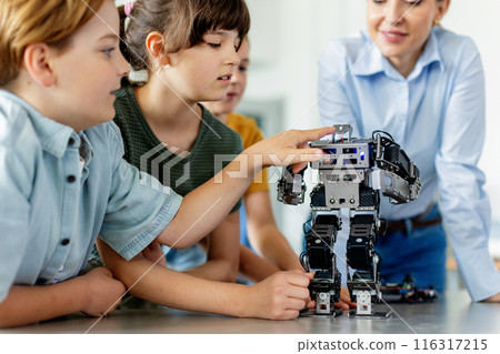 Children learning robotics in Elementary school. Young students building robot in after school robotics club. Field trip to real robotics laboratory. 116317215