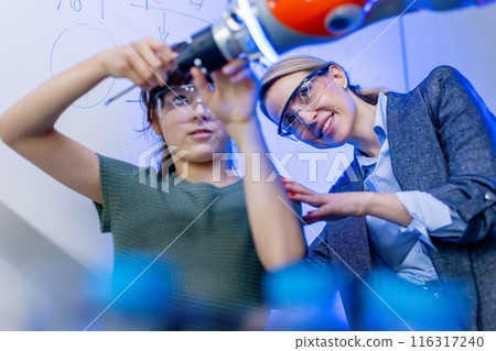 Mom and girl during take your daughter to work day, encouraging daughters in career in robotics. Field trip to real robotics laboratory. Real scientist talking with schoolgirl. 116317240