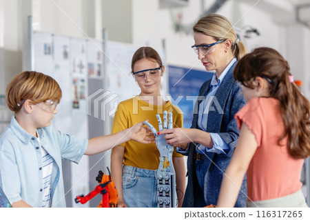 Children learning robotics in Elementary school. Young students building robot in after school robotics club. Field trip to real robotics laboratory. 116317265
