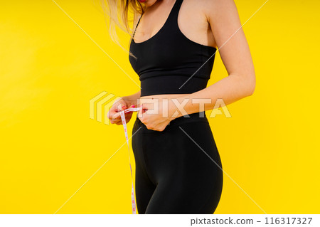 A weight loss and healthy lifestyle concept. Smiling slim woman measuring her waist with tape 116317327