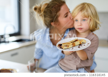 Mom and son eating pancakes together, morning in the kitchen for singel mother. Parents and children spending weekend day indoors. 116318145