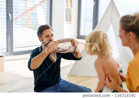Parents putting clothes on small boy, who trying to run off. Nuclear family having fun at home, spending weekend day indoors. Parents putting clothes on small boy, who trying to run off. Nuclear family having fun at home, spending weekend day indoors. 116318192