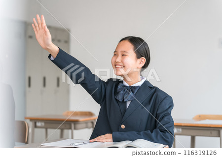 Smiling junior high school, high school, and elementary school girls (uniform) raising hands, opinions, remarks, and questions during class in school classrooms 116319126