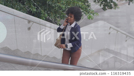 Image of african american woman talking on phone and looking at watch while walking up stairs 116319435