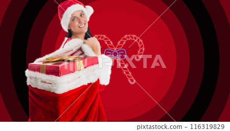 Image of woman in santa outfit with sack of christmas presents over candy canes on red circles 116319829