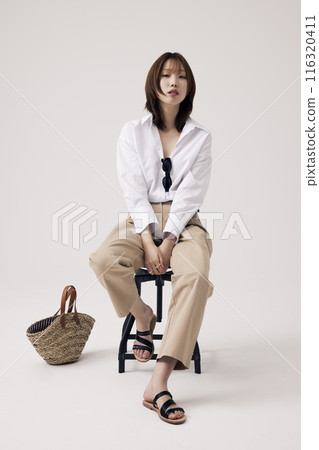 Korean Woman Poses in a Chair With Bags on the Floor 116320411