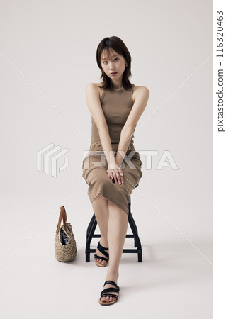 Korean Woman Sitting in Chair wearing Beige Knit Dress 116320463