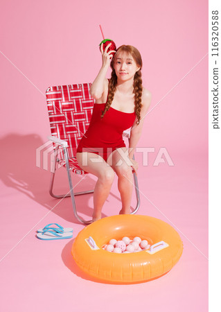 A Korean woman in her 20s who is sitting in a chair wearing a monokini look and holding a drink 116320588