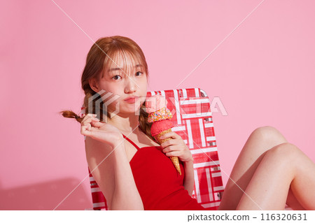 A Korean woman in her 20s who sits on a chair in a monokini look and holds ice cream A Korean woman in her 20s who sits on a chair in a monokini look and holds ice cream 116320631