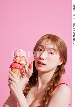 A Korean woman in her 20s holding an ice cream in a pink background 116320688