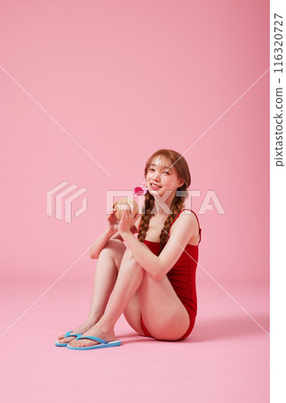 A 20s Korean Woman Sitting on the Floor in a Monokini Look and Holding a Coconut Drink 116320727